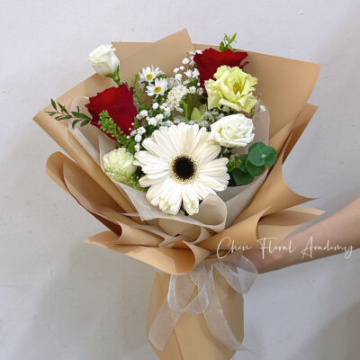 small bouquet with white gerbera daisy and red roses in brown wrapping