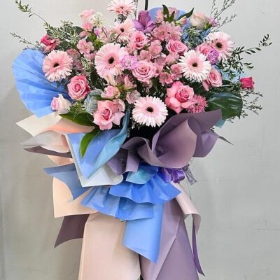 Opening flower tripod stand in blue wrapping with pink flowers